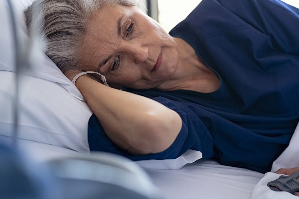 woman over 50 so tired laying in bed awake in the middle of the day