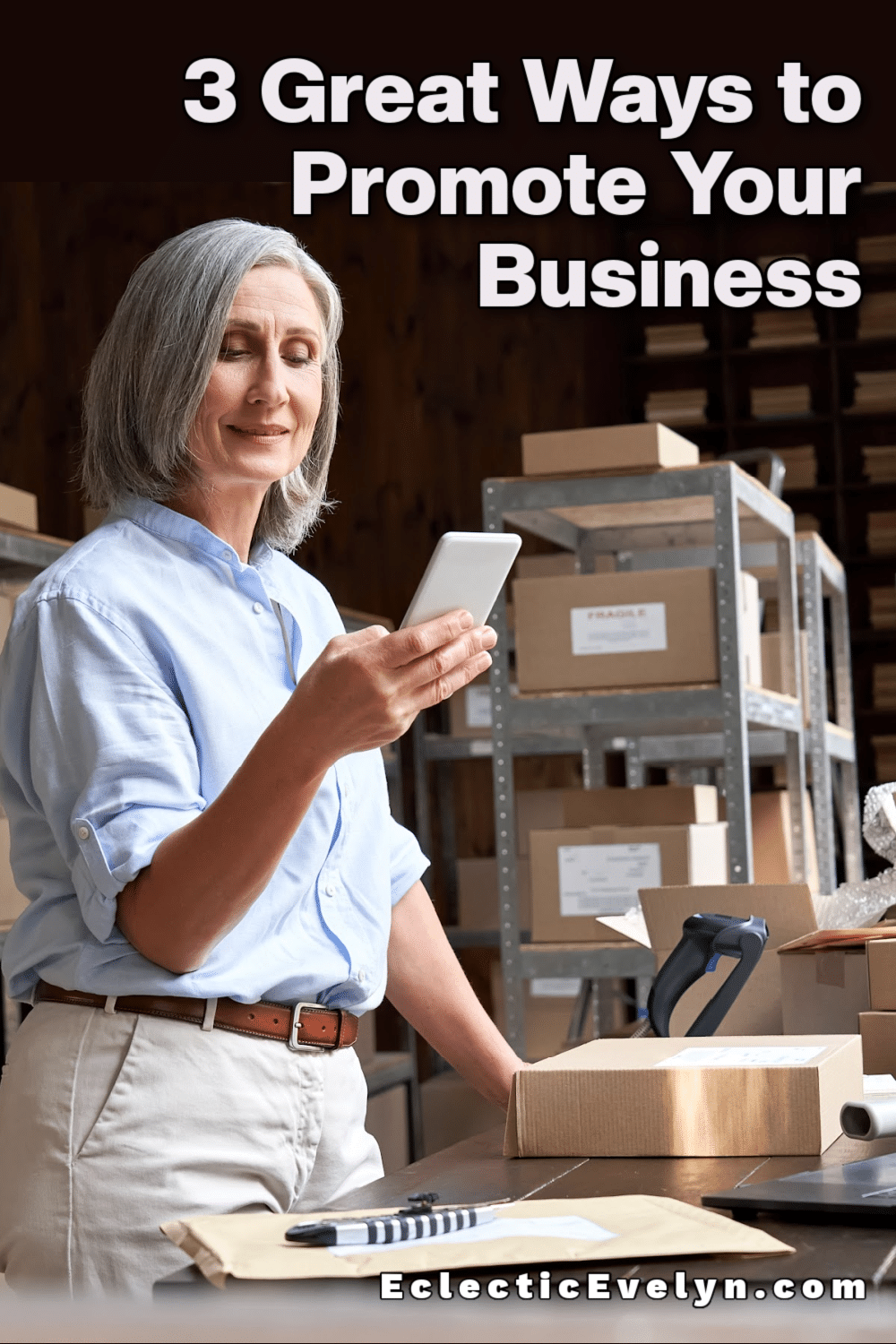 business woman over 50 holding a cell phone in a warehouse full of products