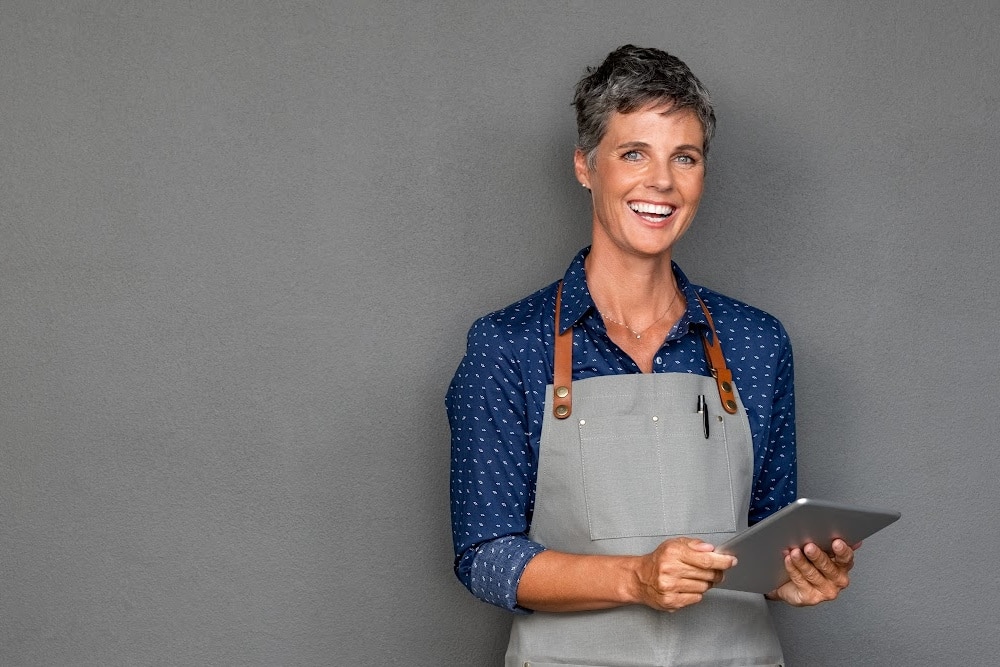 business woman over 50 holding a tablet creating online marketing for her business