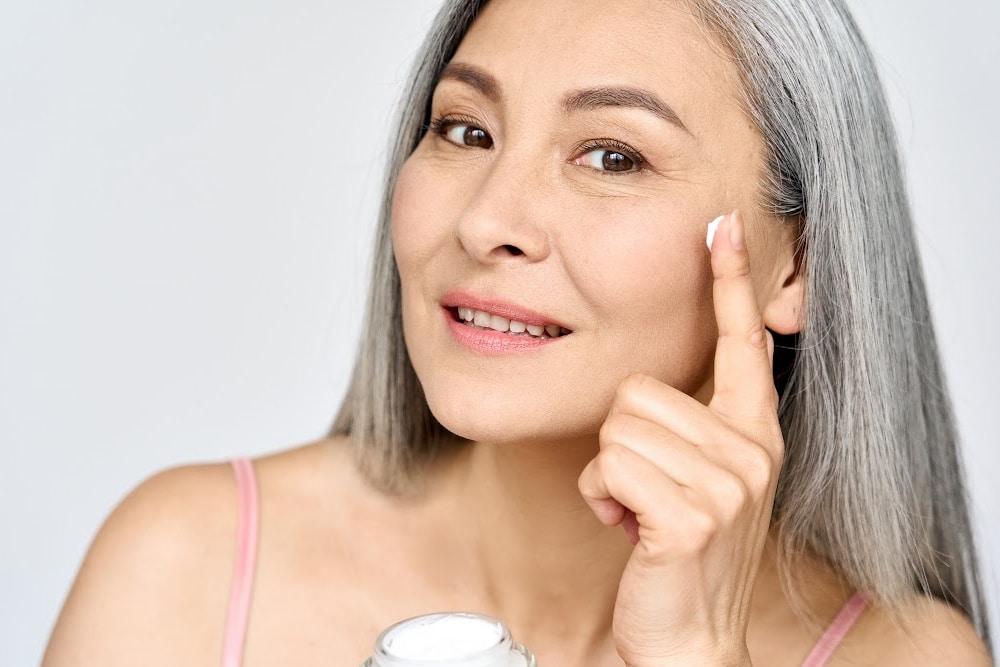 woman over 50 applying a light cream for summer skincare