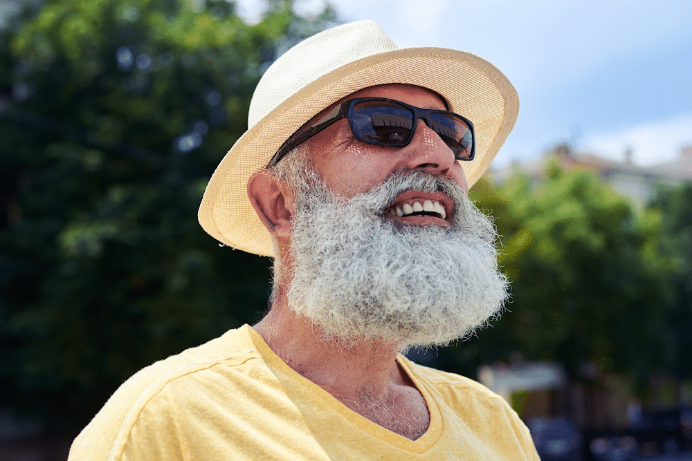 man over 50 outside wearing a hat and sunglasses to protect himself from sun damage