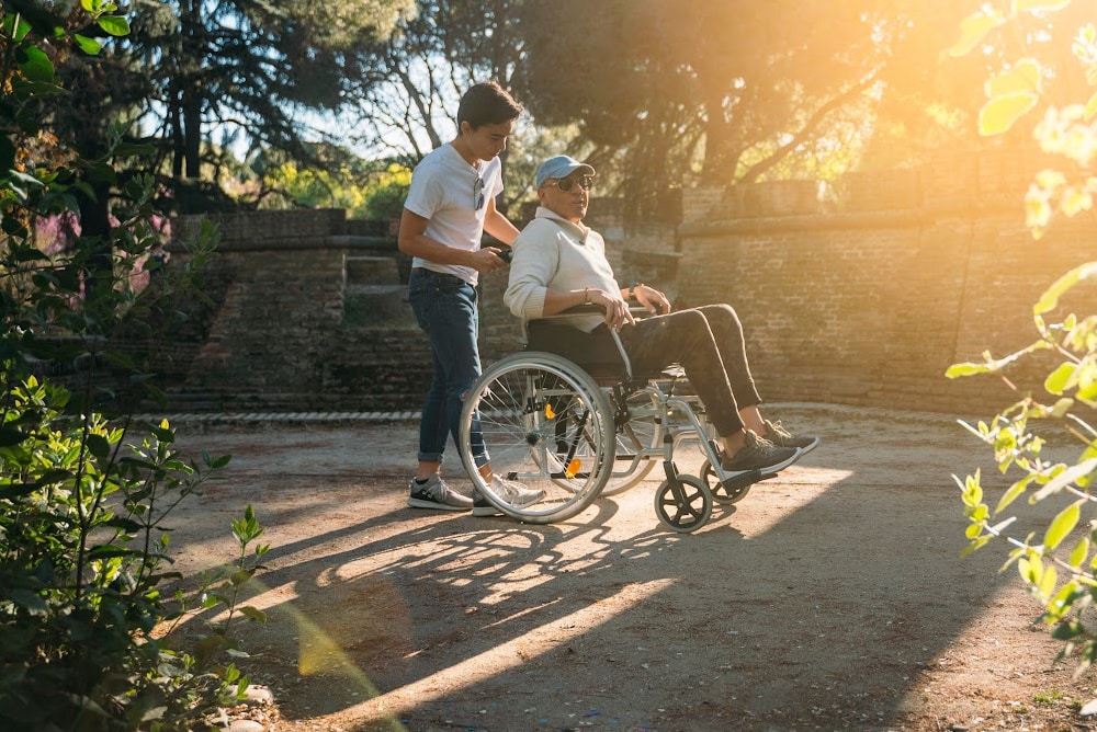 adult son providing caregiver support for disabled veteran father in wheelchair