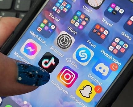 Evelyn Dortch holding her cell phone showing social media apps