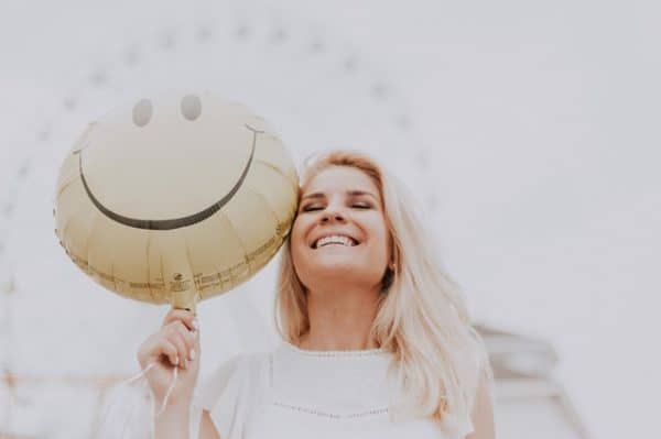 woman hold a balloon with a smiley face on it