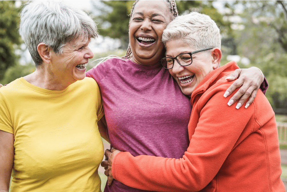 a group of three gen x women over 40 laughing and hugging