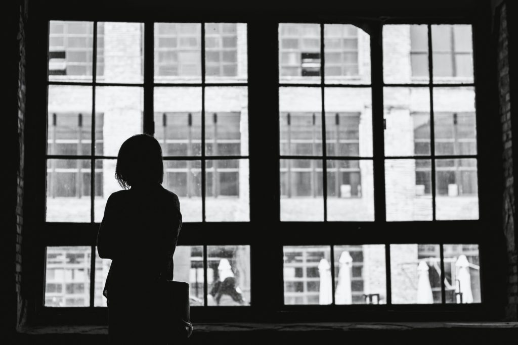 woman looking out the window depressed
