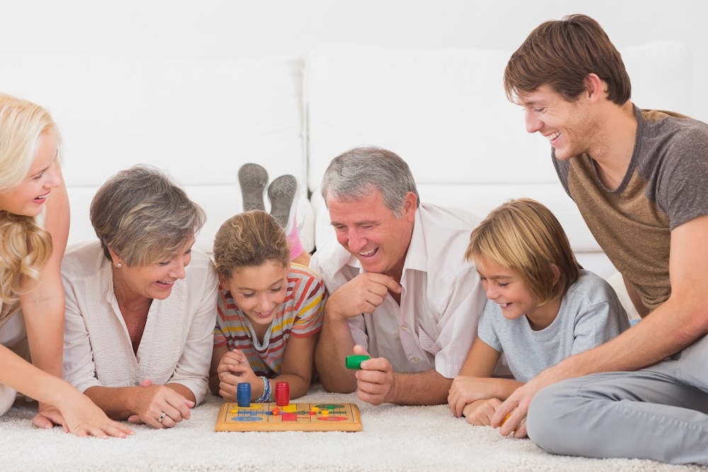 family playing a board game includes grandparents, parents, and children