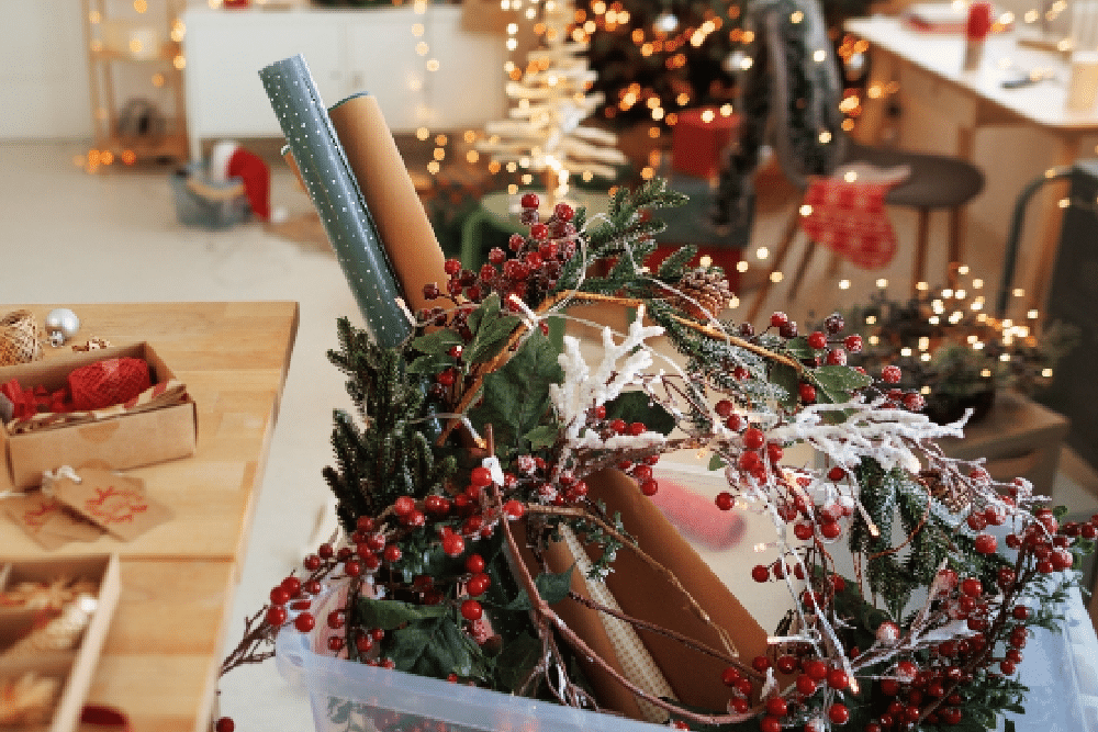 box of Christmas clutter with a Christmas tree in the background in a living room after Christmas mess