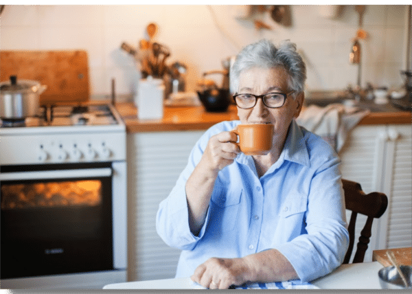 an older woman drinking coffee at a table