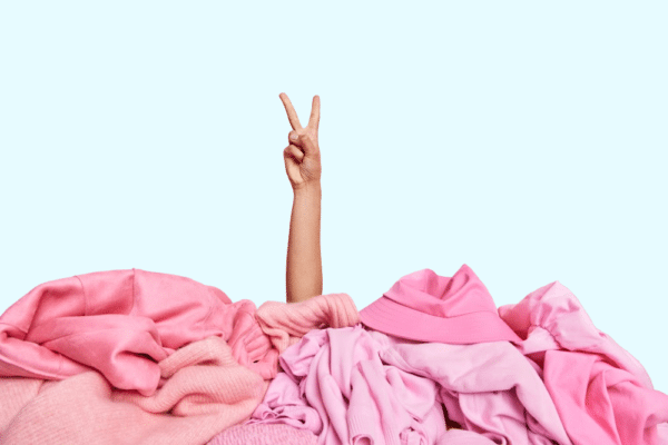a pile of pink laundry with a person's arm sticking out of it. buried in laundry