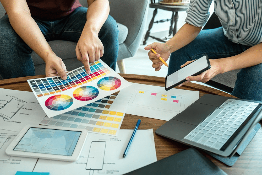 two people discussing what color would be most effective for branding. They are holding colors wheels and have swatches of colors on paper