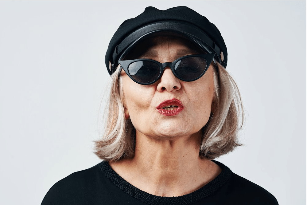 woman over 50 wearing sungalsses red lipstick and a leather motorcycle cap