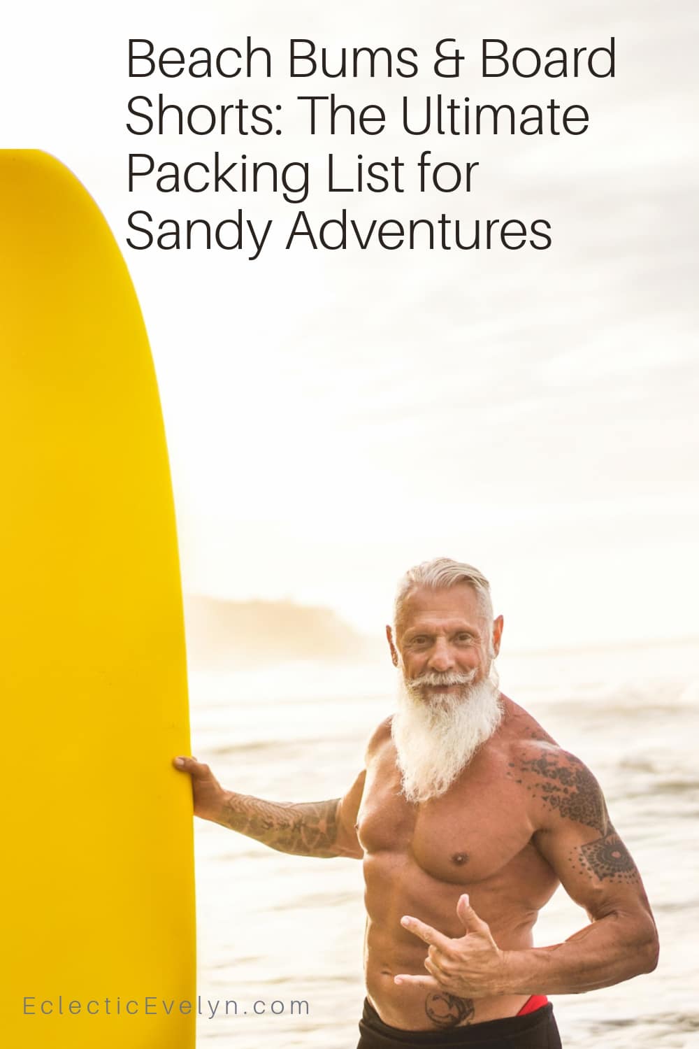 surfer over 50 with a long white beard on the beach with his surfboard giving the hang loose sign.