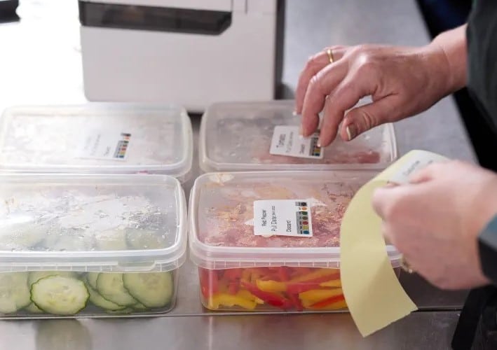woman over 50 putting sticker labels on fresh cut vegetables