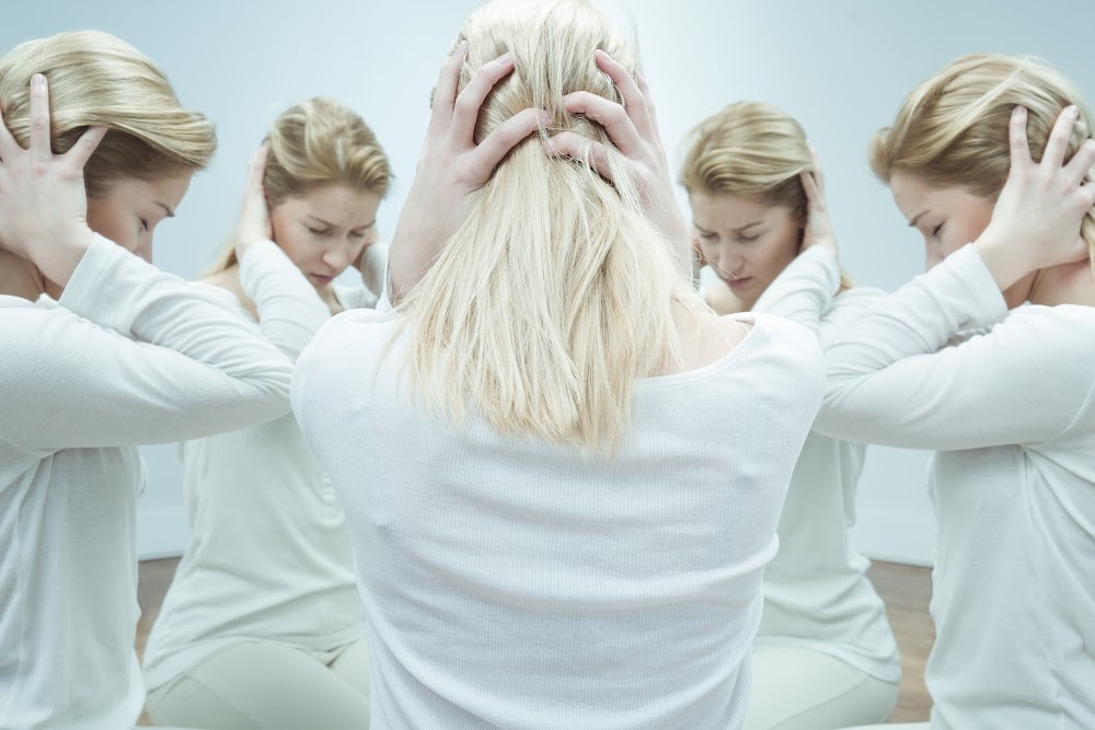 a woman over 40 split into 5 women sitting in a circle clutching her head