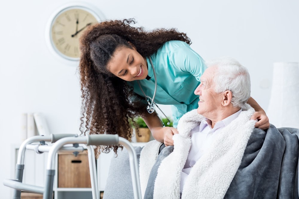 in home health services worker helping an elderly man with a walker