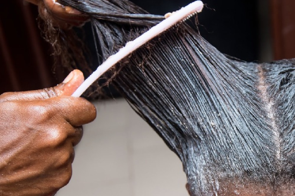 woman over 40 having a hair relaxer applied by a hairstylist