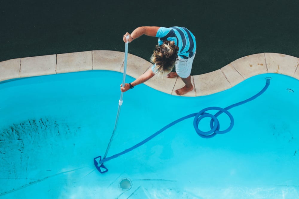 a person cleaning a backyard pool