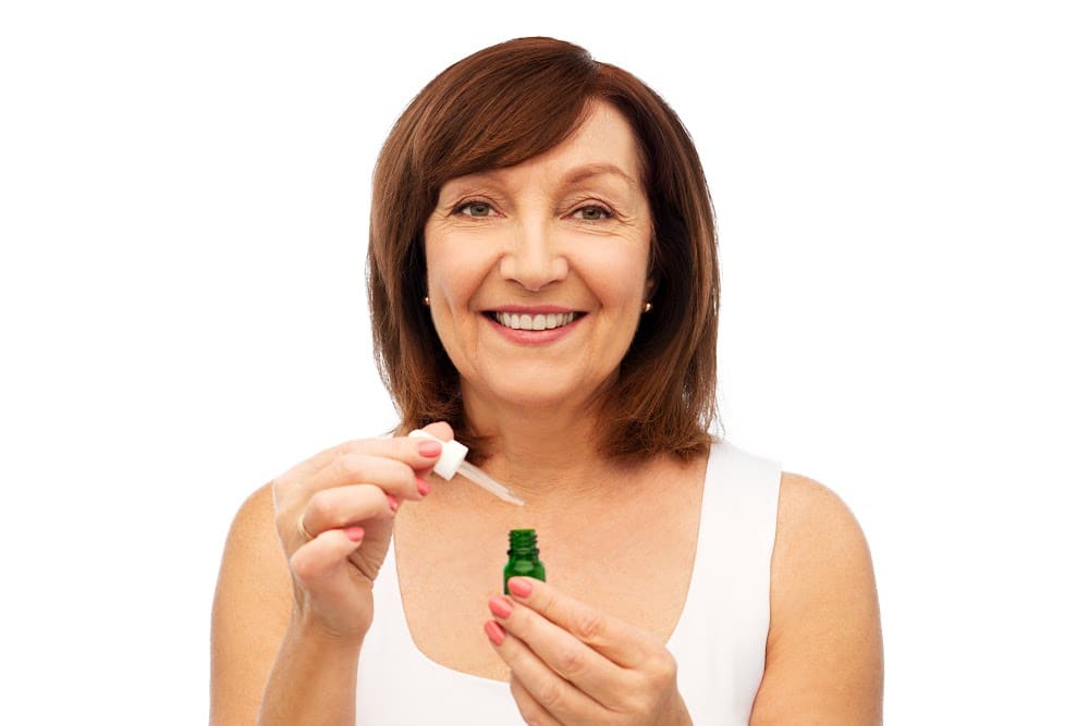 Woman over 50 using CBN CBD CBG cannabinoid oil to help with menopause symptoms