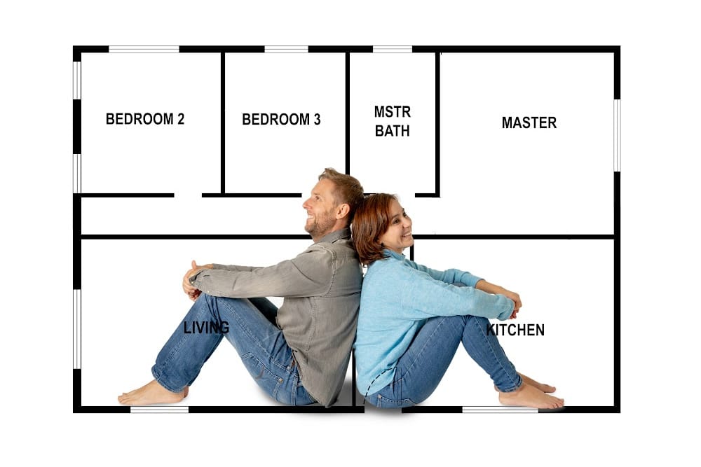 man and woman setting back to back in front a a floor plan