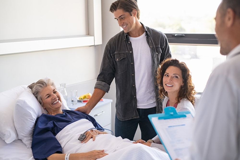 woman over 0 in a hospital bed talking with her family and a doctor