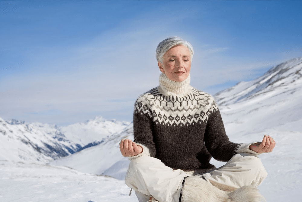 woman over 50 meditating in the snow