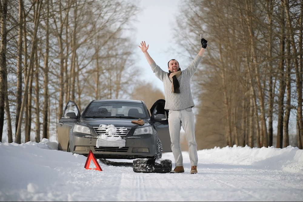 man stranded on the side of the road using items from his winter car emergency kit