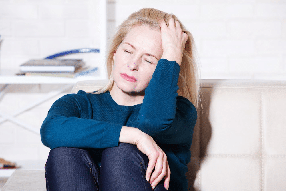 woman over 40 looking stressed out sitting on a couch