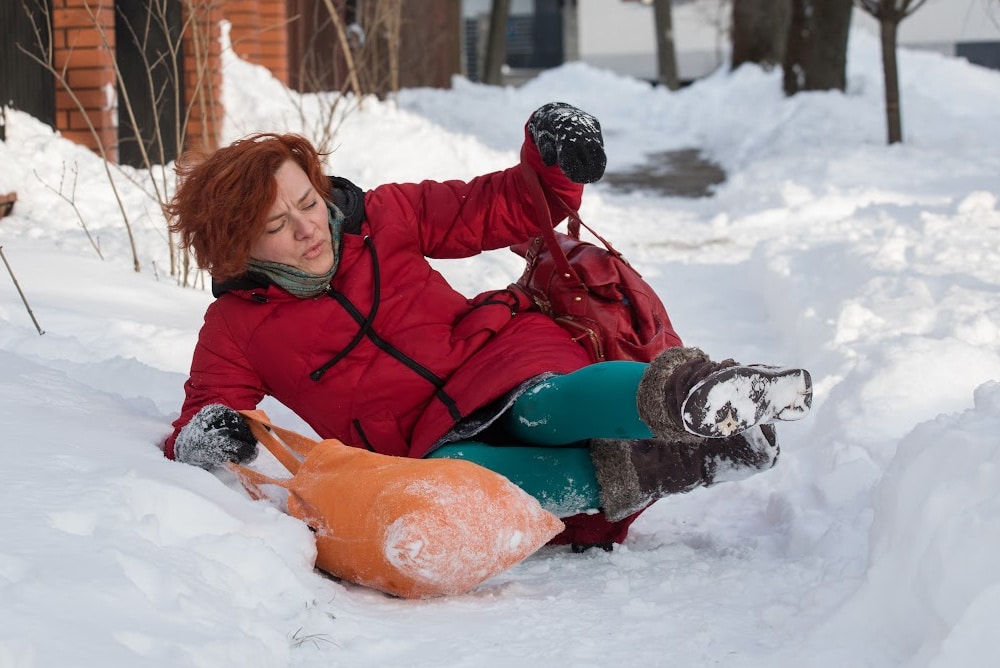 woman over 50 falling on a snow covered sidewalk