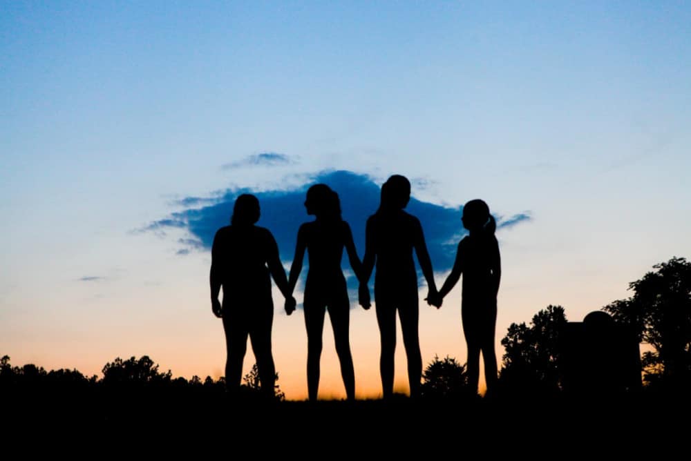 silhouette of 4 women holding hands to take the leap into reinventing themselves.