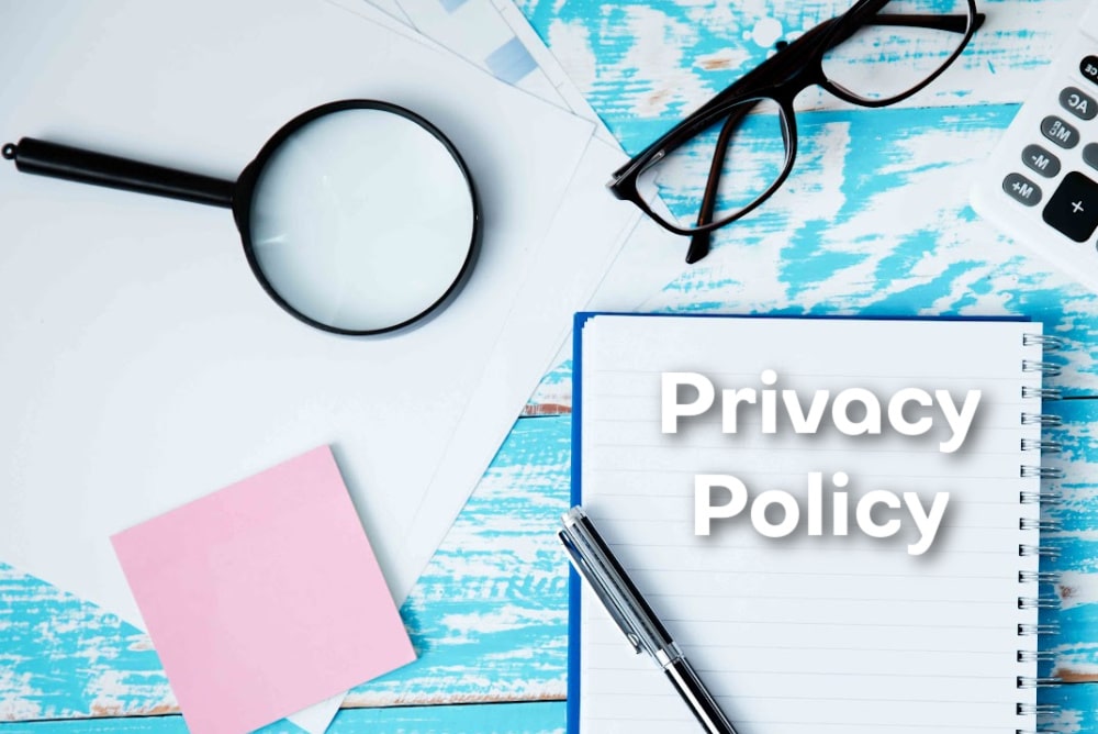 a notebook, glasses, magnifying glasses reading glass a post it note and the words privacy policy